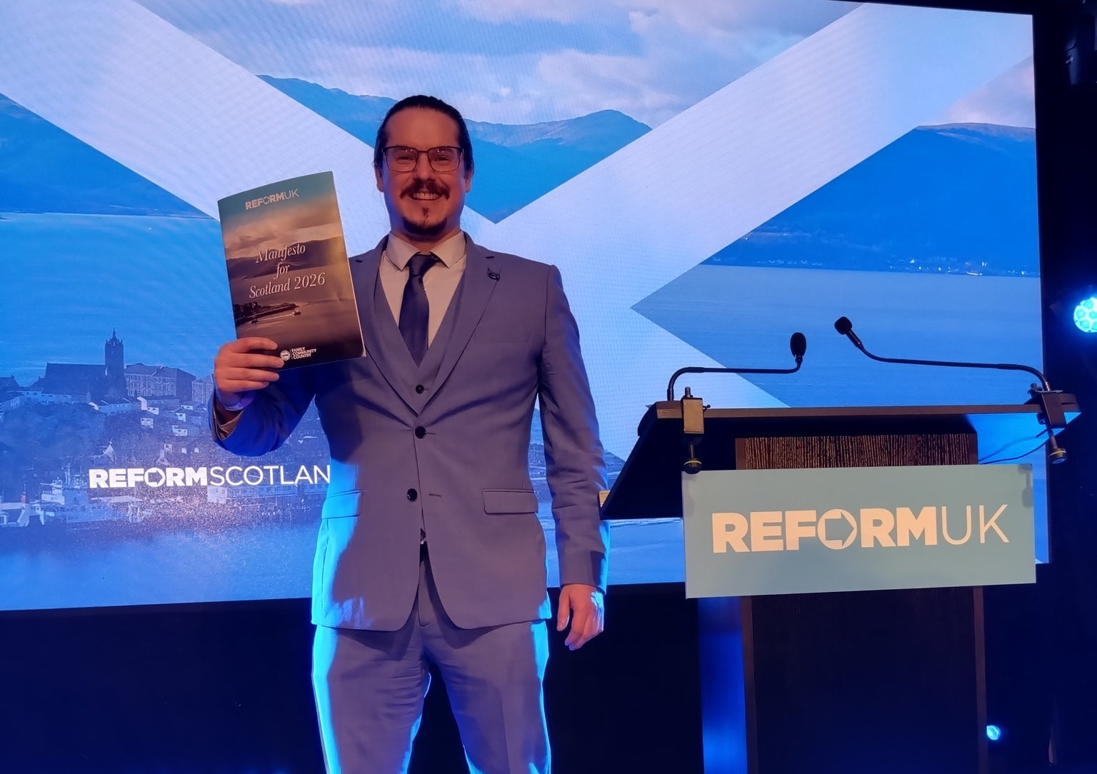 Allan Lyons at Scottish Reform conference holding a manifesto