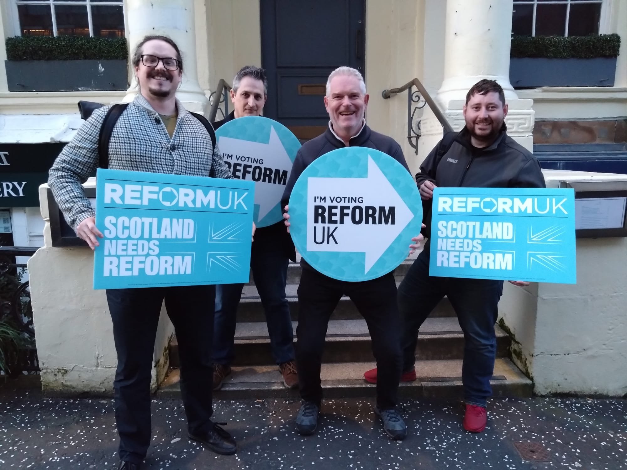 Allan Lyons standing with others holding Reform signs
